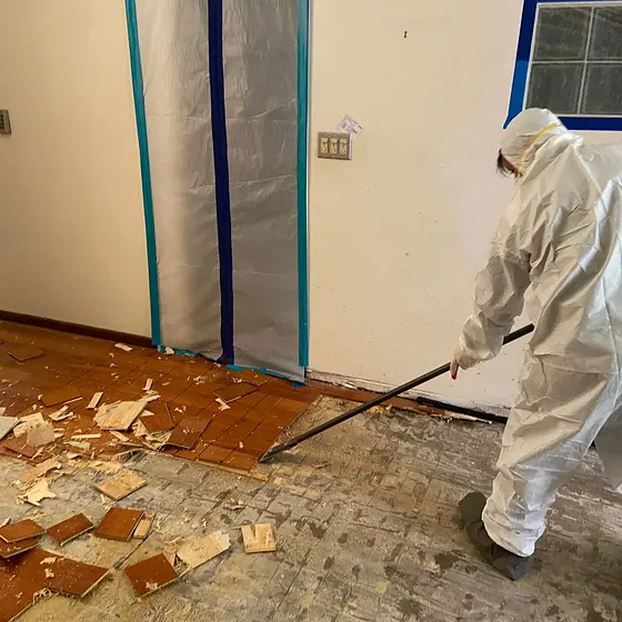 Pulling up damaged flooring in full PPE, Central LA